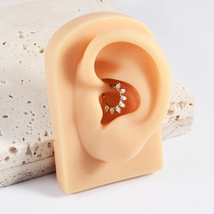Detailed close-up of golden helix hoop earring with marquise cubic zirconia on ear model