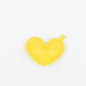 Macro detail of a yellow heart-shaped PU leather keychain with precise stitched edges