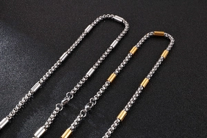 Macro detail of silver and two-tone box chain necklace with polished cylinder link design