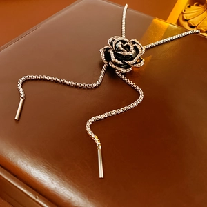 Detailed view of a black camellia brooch with silver rhinestones on a leather texture