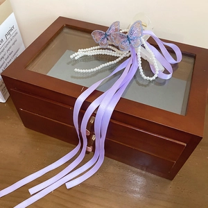 Détail d'une pince à cheveux en ruban de satin lavande avec papillons et perles