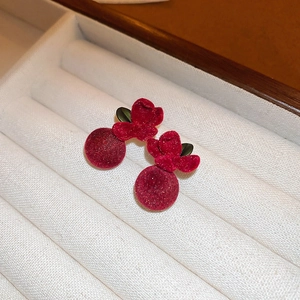 Détail macro de boucles d'oreilles nœuds en velours bordeaux avec perles et feuilles