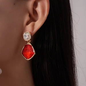 Dettaglio di modella che indossa orecchini vintage in resina con ciondolo rosso