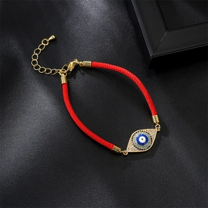 Macro shot of red braided Milan rope bracelet with golden zircon evil eye charm detail