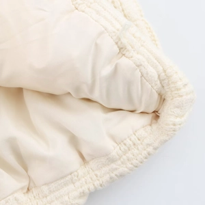 Detail showing the knitted texture and smooth cream lining of the stand-collar vest