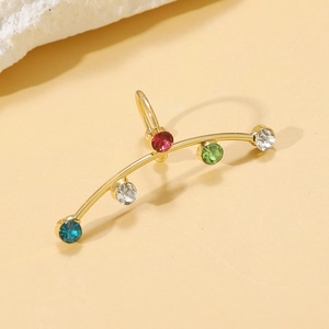 Macro shot of gold-plated ear cuff with colorful zircon inlay and polished metal texture