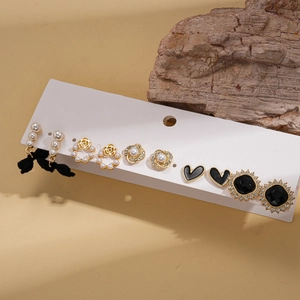 Set of six pairs of gold and black earrings with pearls and velvet bows on a display card