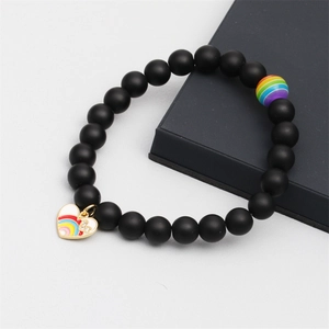 Detail of matte black beaded bracelet with rainbow heart pendant and rhinestone charms