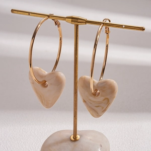 Detail of heart pendants on gold hoops displayed on a professional T-stand