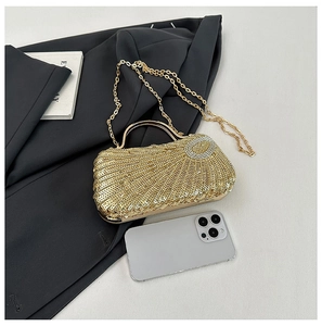 Golden sequin evening clutch with shell texture and metal handle paired with a black suit