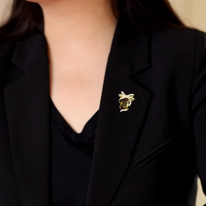 Broche dorée raffinée avec gemme ambrée et nœud ruban sur le revers d'un costume noir
