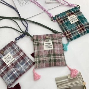 Detail of plaid canvas mini phone bags with tassel accents and colorful woven ropes