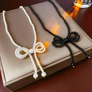 Detailed view of bowknot pearl necklaces in black and white on a luxury gift box