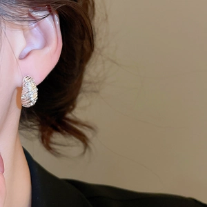 Close-up of elegant silver-colored twisted hoop earring with micro-inlaid zircon on ear