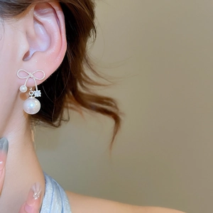 Close-up of bow knot pearl drop earring with zircons worn on model's ear