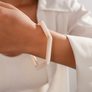 Detail view of a cream resin hexagonal bangle featuring elegant marble texture patterns