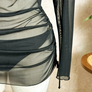 Macro detail of black ruched mesh beach cover-up with textured sheer fabric and drawstring