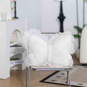 White butterfly plush pillow with lace trim and soft velvet texture on a clear chair