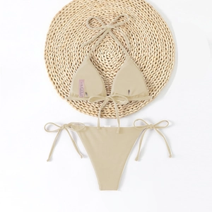Detail of beige ribbed bikini fabric showing vertical texture and adjustable side ties