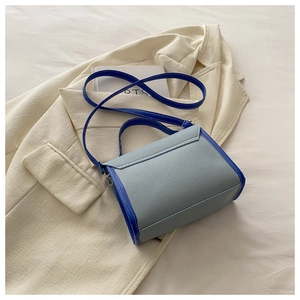 Detail of lychee textured leather and blue edge stitching on stylish square crossbody bag