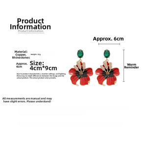 Détail de boucles d'oreilles fleur, pétales rouges, cristal vert et strass étincelants