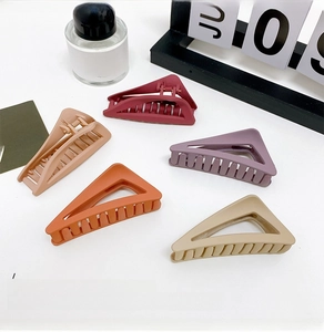 Macro detail of matte triangle hair claws in five Morandi colors on white surface
