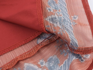 Detail of red floral chiffon fabric with dual-layer lining and high-quality edge stitching
