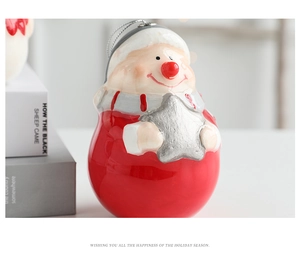 Vue rapprochée d'un Père Noël en céramique rouge brillant tenant une étoile argentée