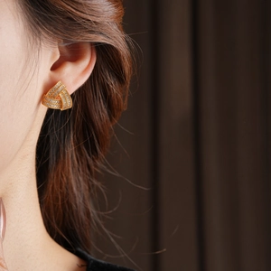 Boucles d'oreilles nœuds triangulaires dorés avec zircons portées par un mannequin