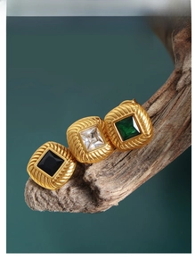 Close-up of vintage square stud earrings with emerald, black, and clear gemstones