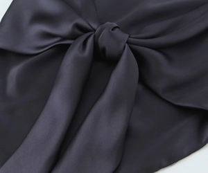 Gros plan détaillé sur le satin anthracite montrant un nœud élégant avec des reflets soyeux
