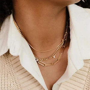 Gros plan d'un collier à trois rangs plaqué or 18 carats avec maille serpent et trombone