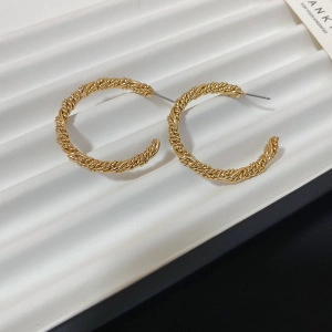 Detailed macro view of gold plated twisted rope C-shaped hoop earrings with woven texture