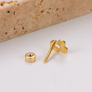 Détail d'une boucle d'oreille cœur évidée en or avec fermoir sur surface en pierre