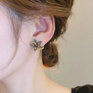 Vintage gold Saturn earrings with black rhinestones and brown bead on female model