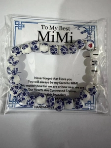 Bracciale artigianale con perle di ceramica blu e lettere MIMI su un cartoncino da esposizione