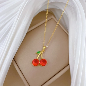 Vue détaillée d'un collier pendentif cerise rouge sur un tissu en soie blanche élégant