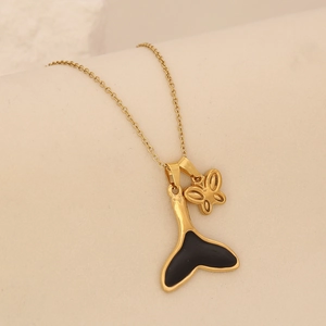 Close-up of golden stainless steel fishtail pendant and hollow butterfly necklace detail