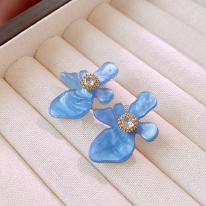 Macro view of blue flower stud earrings with resin petals and sparkling rhinestones