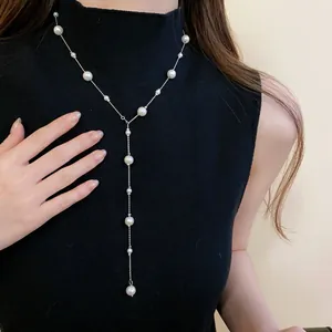 Elegant French-style long faux pearl Y-necklace with silver chain on black turtleneck