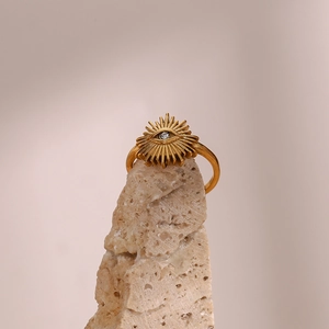 Macro shot of gold-plated stainless steel devil's eye ring with zircon on a stone