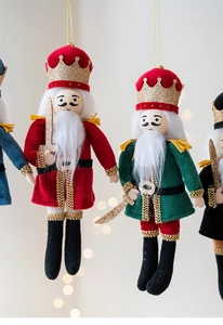 Detailed plush nutcracker ornaments with gold sequins and hanging cords for Christmas trees