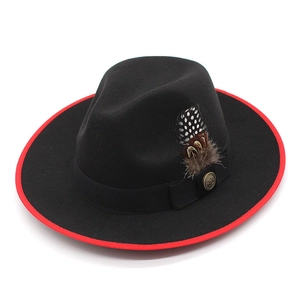 Detail of black fedora hat featuring red brim binding, feather trim and vintage button
