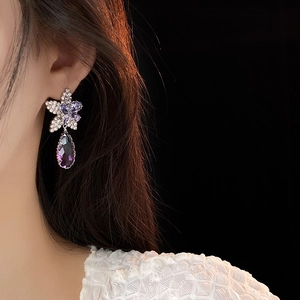 Vue macro des boucles d'oreilles fleur en argent avec cristal violet sur un mannequin