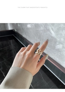Close-up of golden leaf ring with white shell inlay worn against a grey marble wall