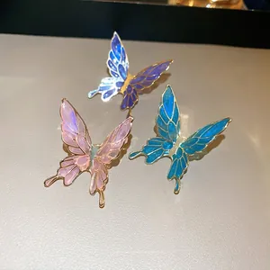 Three gradient butterfly ear cuffs with gold plating on light beige leather surface