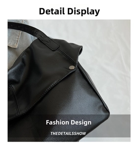 Detail of black litchi grain leather shoulder bag with metallic cylinder button closure