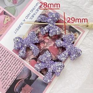 Macro detail of a 28mm by 29mm purple rhinestone bow charm for DIY jewelry and hair accessories