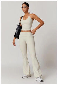 Detail of cream halter crop top and high-waisted flared yoga pants set with smooth texture