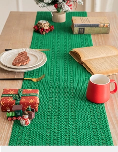 Detail of green woven Christmas table runner with festive texture on a wooden dining table